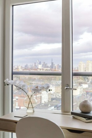Stadtsicht durch ein Fenster, mit einem Schreibtisch, einer Blumenvase und einem kugelförmigen Gegenstand.