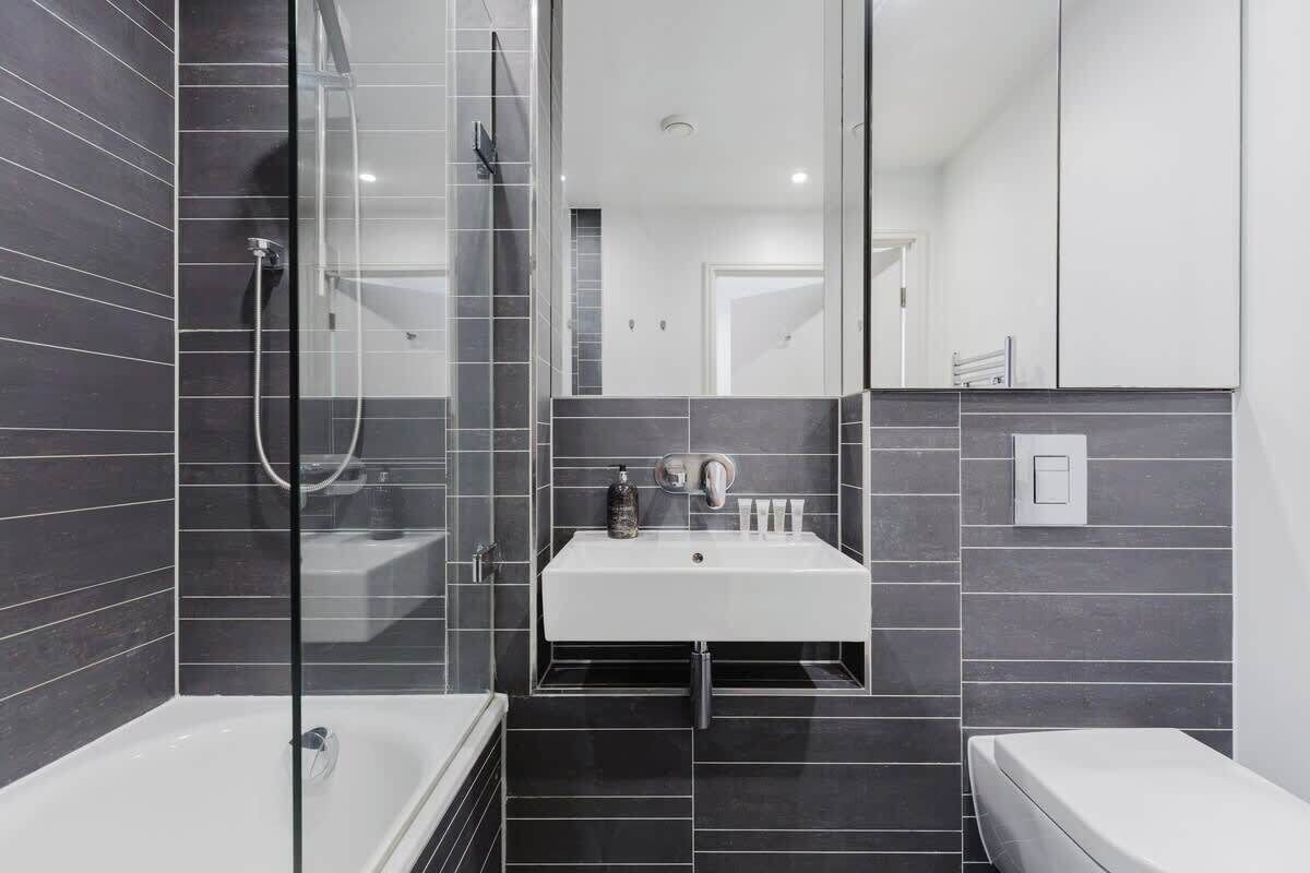 A modern bathroom with a glass-enclosed shower, a white sink, and a mirror.
