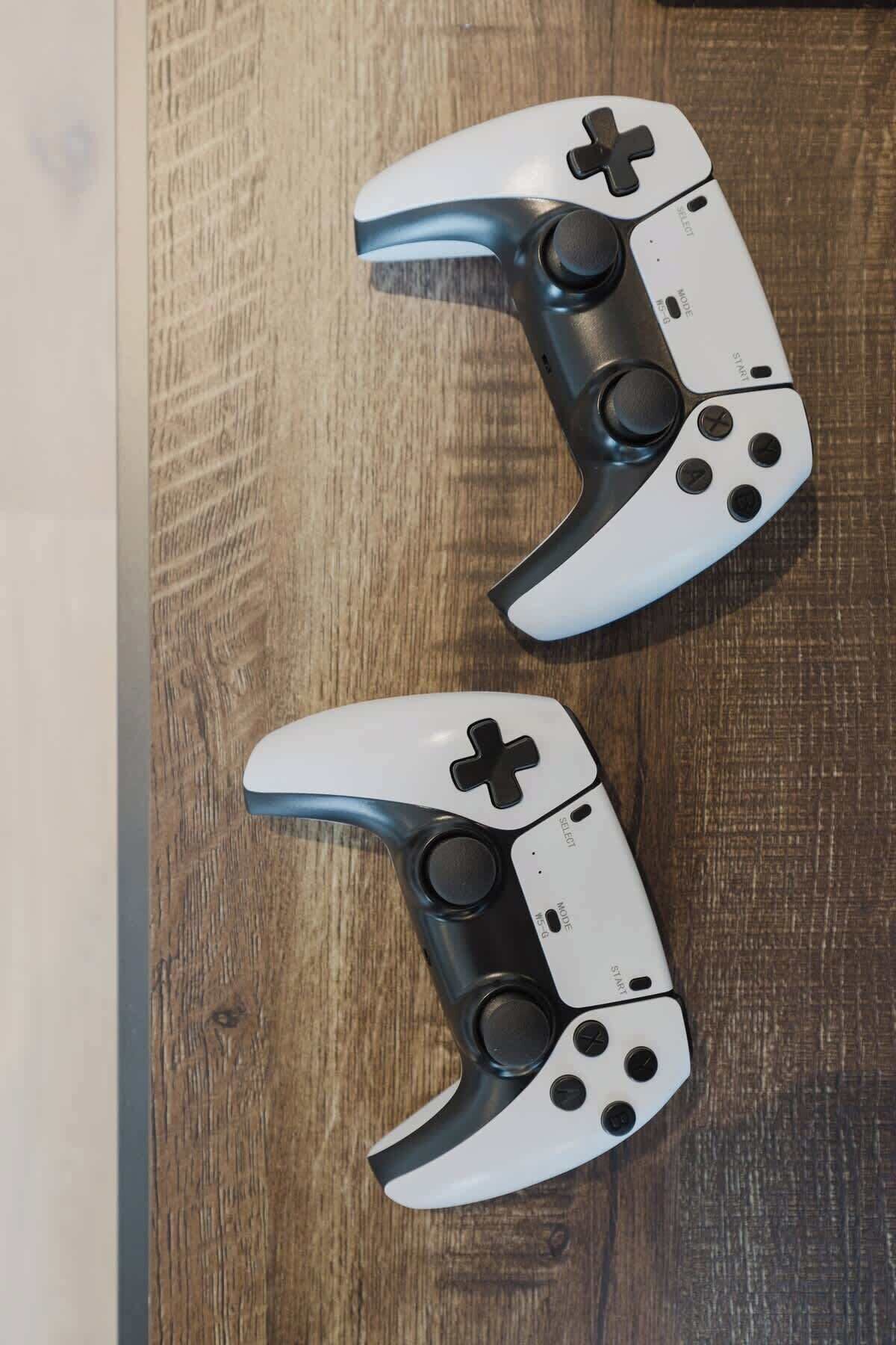 Two white and black game controllers on a wooden surface.
