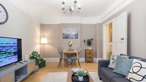Un salon comprenant un téléviseur, un canapé, une table basse et un coin repas.