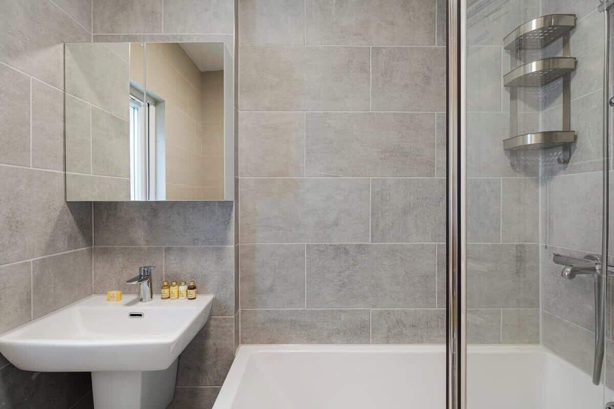 A bathroom with a white sink, mirror, and shower.