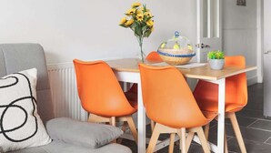 Een eetgedeelte met een tafel, stoelen, een klok en een bank.