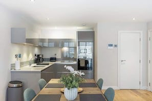 Eine moderne Küche mit Edelstahlgeräten, einem Esstisch mit Stühlen und einem Blumentopf.