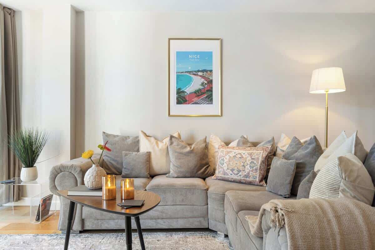 Una sala de estar moderna con un sofá, una mesa de centro, una lámpara y un cuadro en la pared.