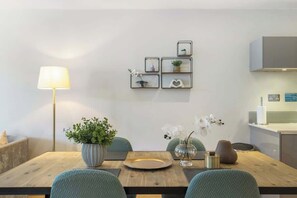 Ein Essbereich mit einem Holztisch, Stühlen, einer Lampe und Wandregalen mit dekorativen Gegenständen.