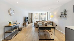 Uma sala de estar moderna com área de jantar, televisão e estante de livros.