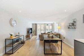 Ein modernes Wohnzimmer mit Essbereich, Fernseher und Bücherregal.
