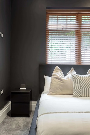 A bedroom with a bed, bedside tables, and a window with blinds. - Delightful 1Bed-Private Patio-FR Parking-PingPong (Greater London)