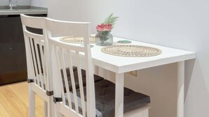 A white dining table with two chairs, a small potted plant, and a vase with flowers. - Delightful 1Bed-Private Patio-FR Parking-PingPong (Greater London)