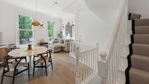 Un interior moderno con comedor, una escalera y vistas a zonas verdes.