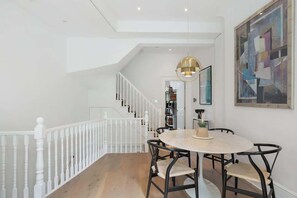 A dining area with a round table, black chairs, and a white railing. - 2bed/2BR w/AC & Stunning Views - Clapham Common (Greater London)