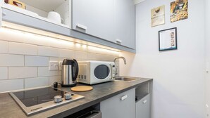 Een moderne keuken met een geïntegreerde inductiekookplaat, een magnetron en een waterkoker.