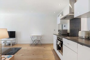 Eine moderne Küche mit weißen Schränken, einer Mikrowelle, einem Toaster und einer kleinen Essecke mit Stuhl und Tisch.
