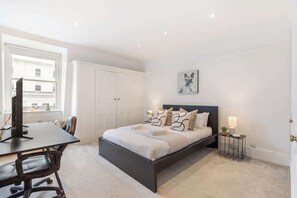 A bedroom with a bed, bedside table, lamp, and a window. - Stunning 2BR - South Kensington (Greater London)