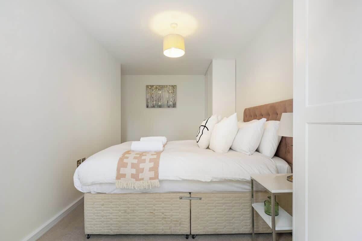 A bedroom with a bed, bedside table, and a wall-mounted artwork.