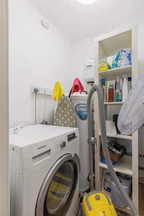 A laundry area with a Siemens washing machine, a Cledh stainless steel detergent, and a vacuum cleaner. - Gorgeous 2BR2BA w Balcony & AC Clapham North (Greater London)