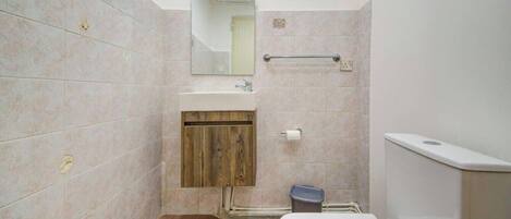 Une salle de bain équipée d’un lavabo, d’un miroir, d’un porte-serviettes et de toilettes.