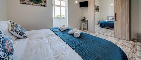 Un dormitorio con cama, escritorio, silla y televisor.