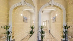 Um corredor com arcos, ladrilhos estampados e vasos de plantas.