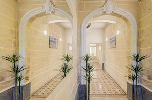 A hallway with arches, patterned floor tiles, and potted plants.