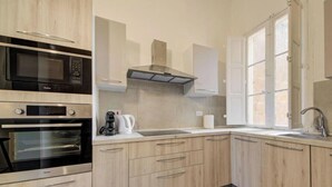 Cozinha com eletrodomésticos embutidos, janela e piso estampado.