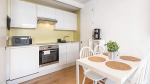 A compact kitchen with white cabinets, a microwave, an oven, and a coffee maker. - Luxe 1BD + A/C | King Bed & 75" TV | Notting Hill (Greater London)