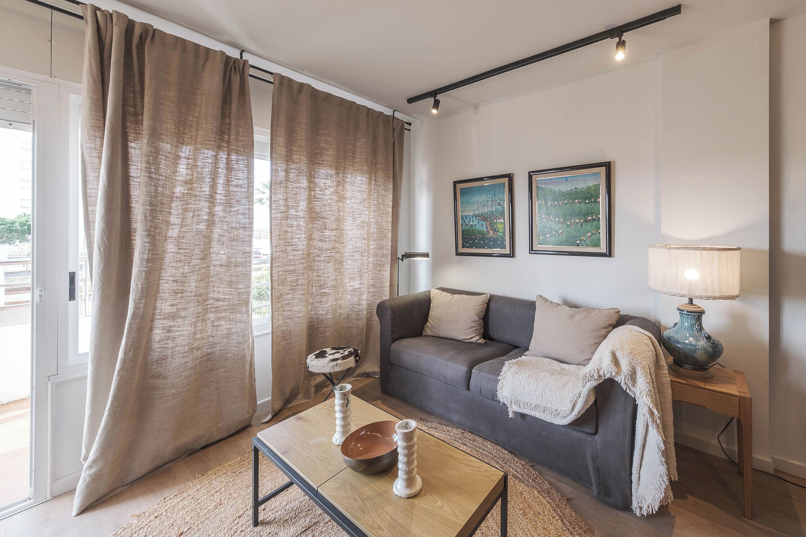 A living room with a sofa, a coffee table, a lamp, and two framed pictures on the wall.