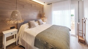 Ein modernes Schlafzimmer mit einem Holz-Kopfteil, einem großen Bett mit grüner Bettdecke, zwei Nachttischen und einer hängenden Leuchte.