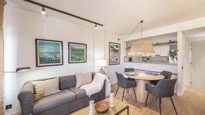 Ein modernes Wohnzimmer mit Sofa, Couchtisch und Essbereich mit Stühlen.