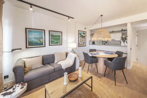 Ein modernes Wohnzimmer mit Sofa, Couchtisch und Essbereich mit Stühlen.