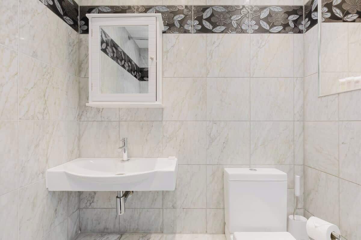 Une salle de bain avec un lavabo blanc, des toilettes et un miroir.