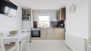 Una cucina funzionale con microonde, piano cottura e lavandino, un tavolo da pranzo con sedie e una finestra con vista.
