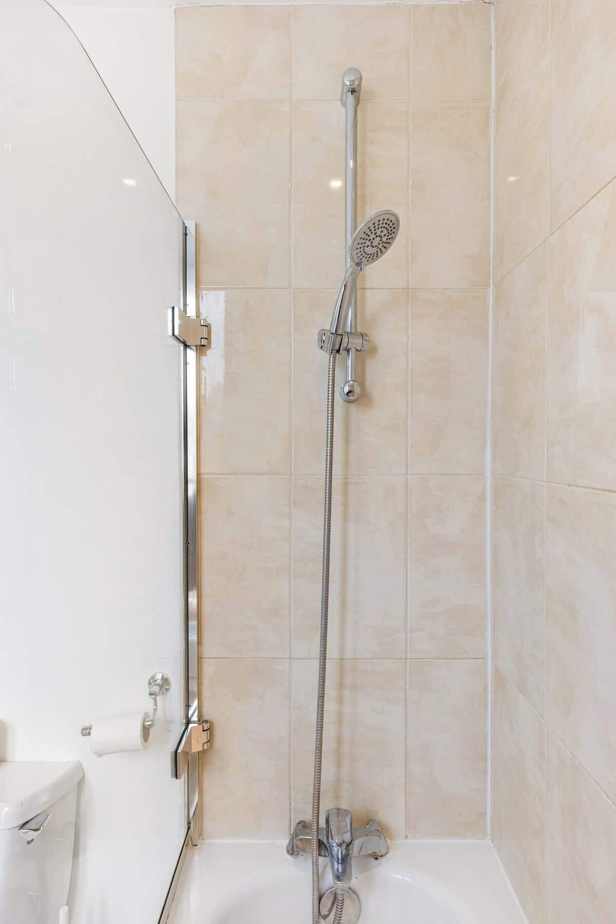 Un baño moderno con ducha, inodoro y mampara de vidrio.
