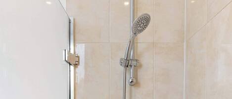 Un baño moderno con ducha, inodoro y mampara de vidrio.