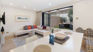 Een moderne woonkamer met een bank, eettafel en uitzicht op het omliggende landschap.