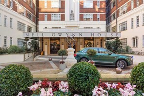 The entrance of Nell Gwynn House with a green car parked in front, a statue, and well-maintained gardens. - CHELSEA JEWEL (Greater London)