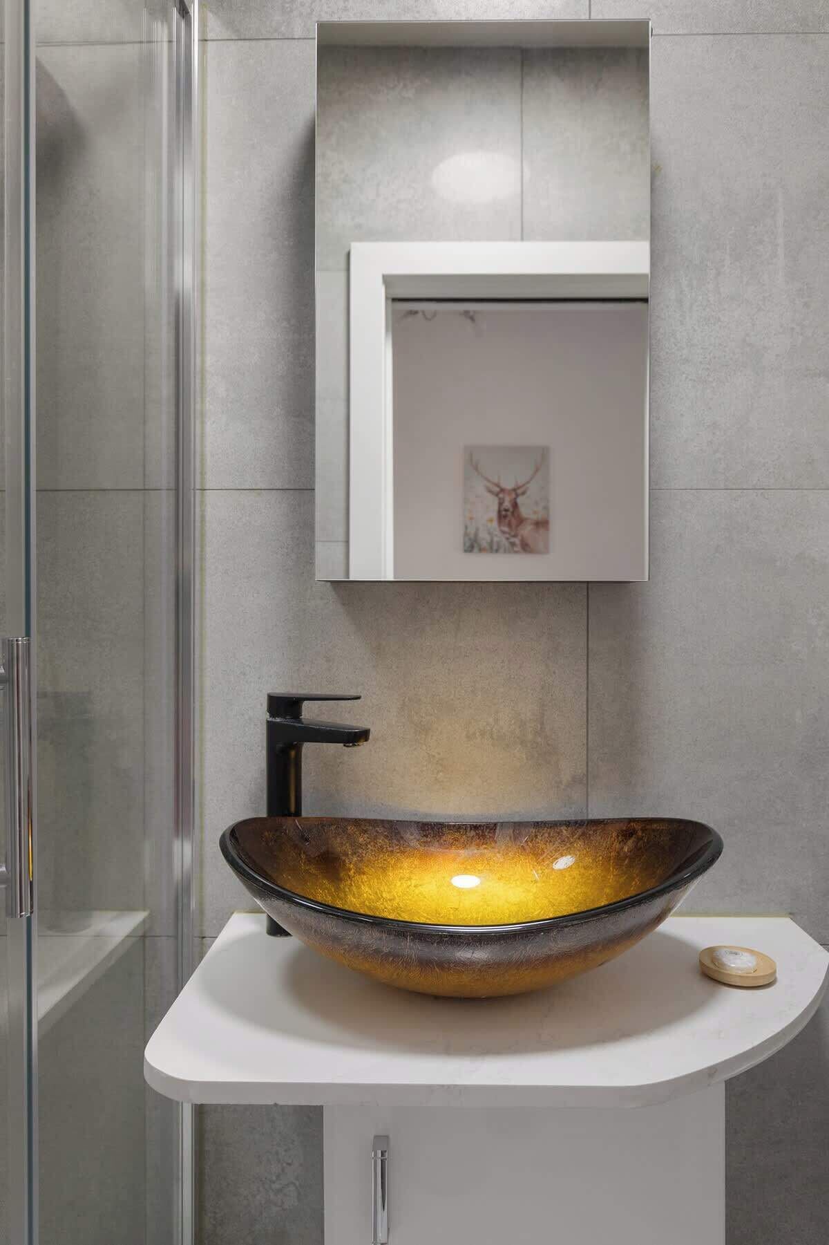 Une salle de bain avec un lavabo en forme de bol en verre, un meuble blanc et un tableau encadré au mur.