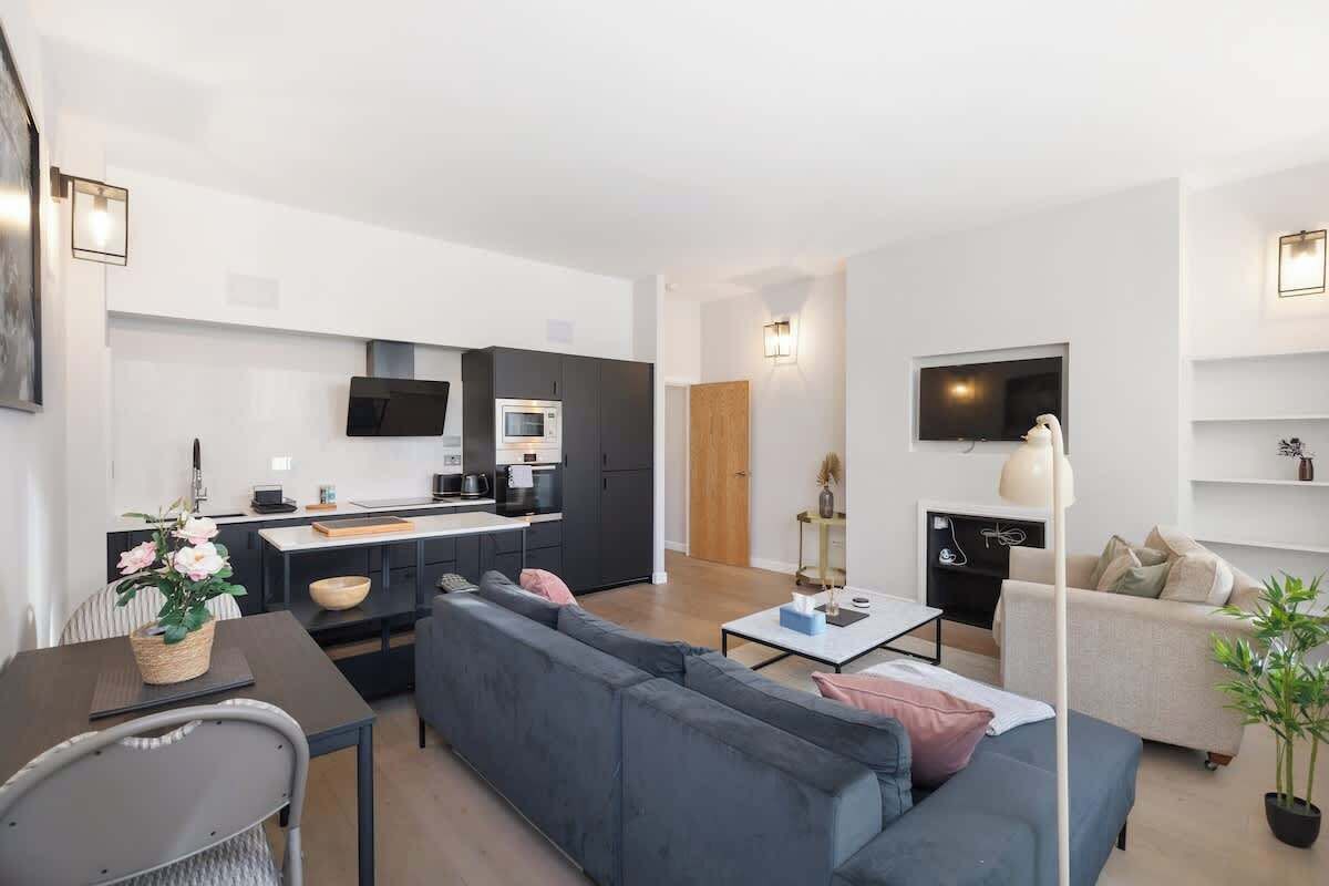 A modern living space with a kitchen, sofa, dining table, and TV.
