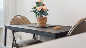 Ein Essbereich mit Tisch, Stühlen, einem gewebten Blumentopf und einem gerahmten Stadtbild an der Wand.