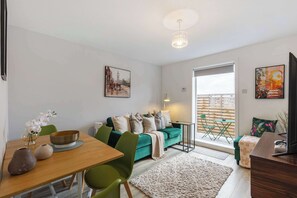 A modern living room with a sofa, dining table, chairs, and artwork on the walls. - Chic 2Bed w/Balcony - Kensal Rise (Greater London)