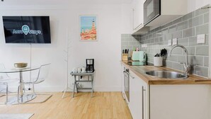 Et moderne køkken med mikroovn, vask og kaffemaskine på et lille bord.