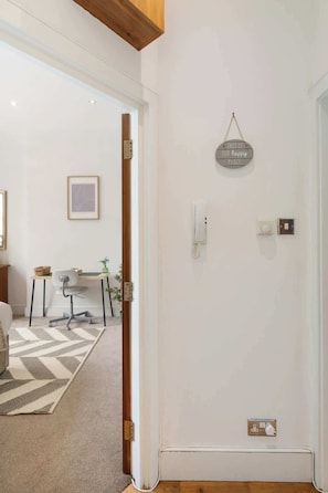 Ein Zimmer mit Tür, Lichtschalter, Thermostat und einer Wandleuchte.