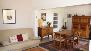 Ein Wohnzimmer mit einer Couch, einem Holzessttisch, Stühlen, einem Couchtisch, einem Teppich und einem Schrank.