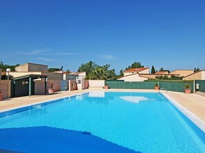 A clear blue swimming pool surrounded by buildings, a covered area, and a green fence. - St Cyprien, superb bright apartment with large terrace (Saint-Cyprien)
