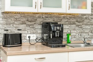 A kitchen with a stone wall, a coffee machine, a toaster, and a sink. - Apartment 'Otter' with Balcony and Wi-Fi (Lachendorf)