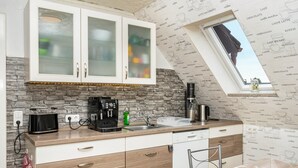 Una cocina con protector contra salpicaduras de piedra, una cafetera y un ventanal con vistas.
