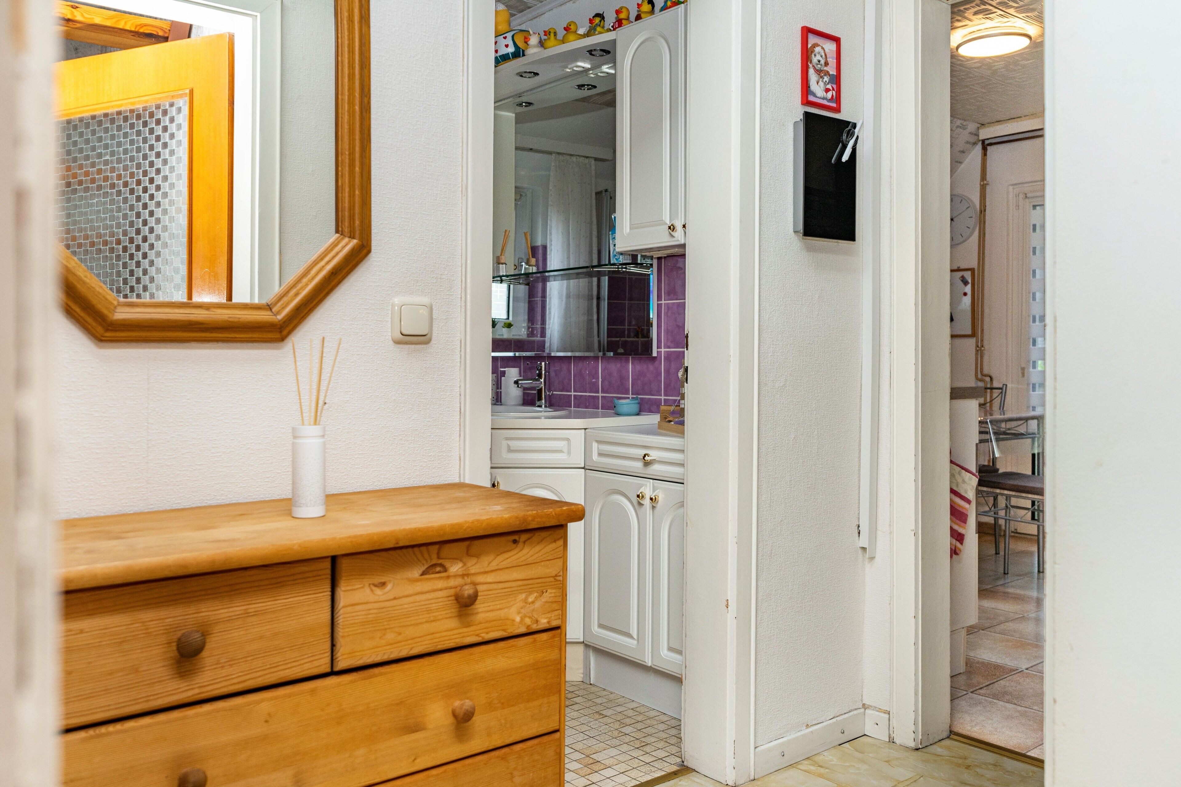 A kitchen with white cabinets, a wooden countertop, and a mirror.