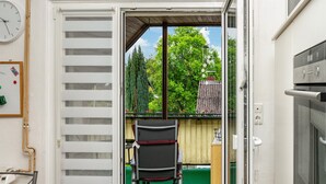 Una habitación con puerta corredera que da a un balcón, una silla y una mesita.