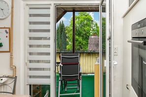 Ein Zimmer mit einer Schiebetür, die auf einen Balkon führt, einem Stuhl und einem kleinen Tisch.