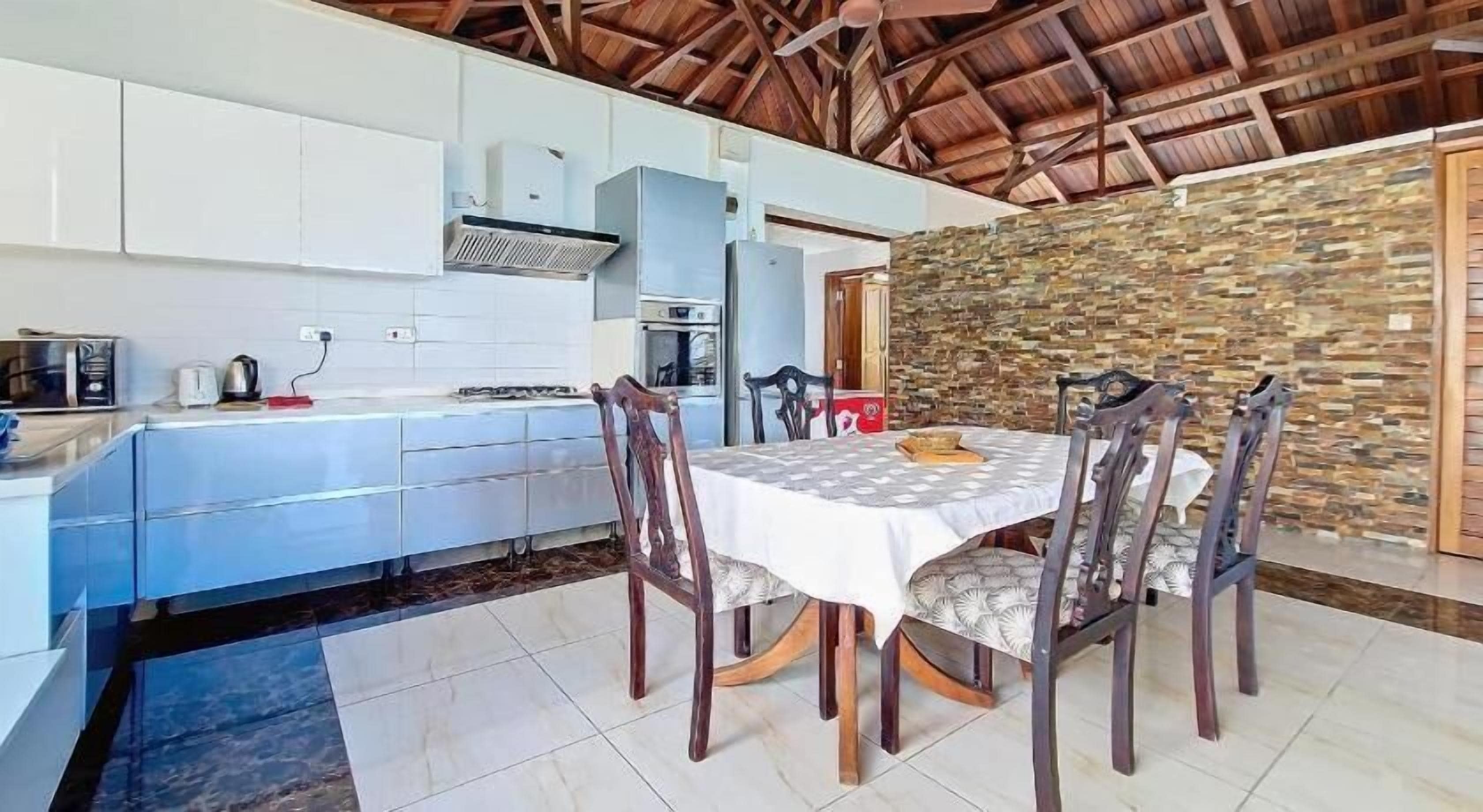 A modern kitchen with white cabinets, a built-in oven, and a dining area with a table and chairs.